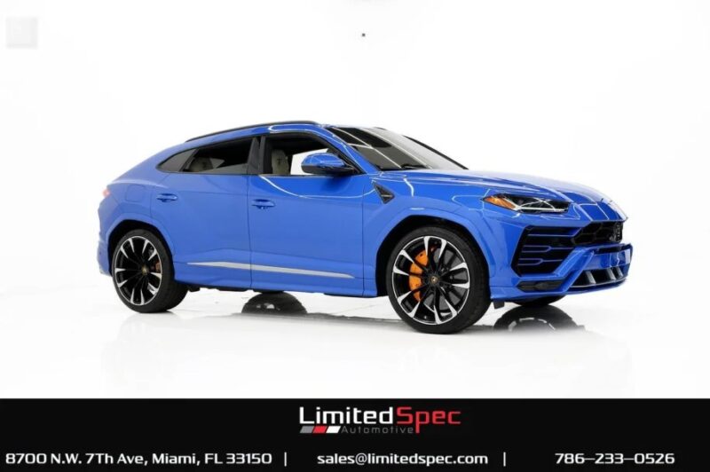 A sleek blue SUV, reminiscent of the Lamborghini Urus, boasts black and orange rims as it stands elegantly in a studio setting. Contact details and the logo of LimitedSpec Automotive are displayed below, indicating it's for sale.