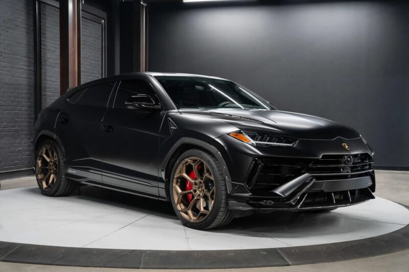 A matte black Lamborghini Urus with bronze wheels and red brake calipers sits indoors on a circular platform, showcasing why it’s among the best Lamborghini SUVs for sale.