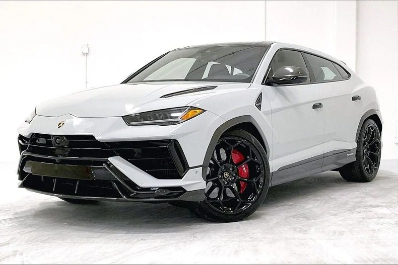 A white Lamborghini Urus SUV with black wheels and red brake calipers is parked in a white indoor space, showcasing why it's considered one of the best Lamborghini SUVs for sale today.