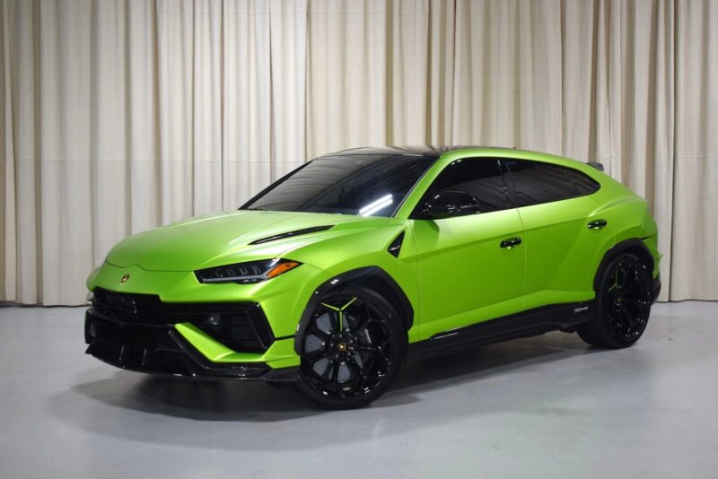A bright green Lamborghini Urus SUV, one of the best Lamborghini models, is parked indoors on a white floor in front of beige curtains.