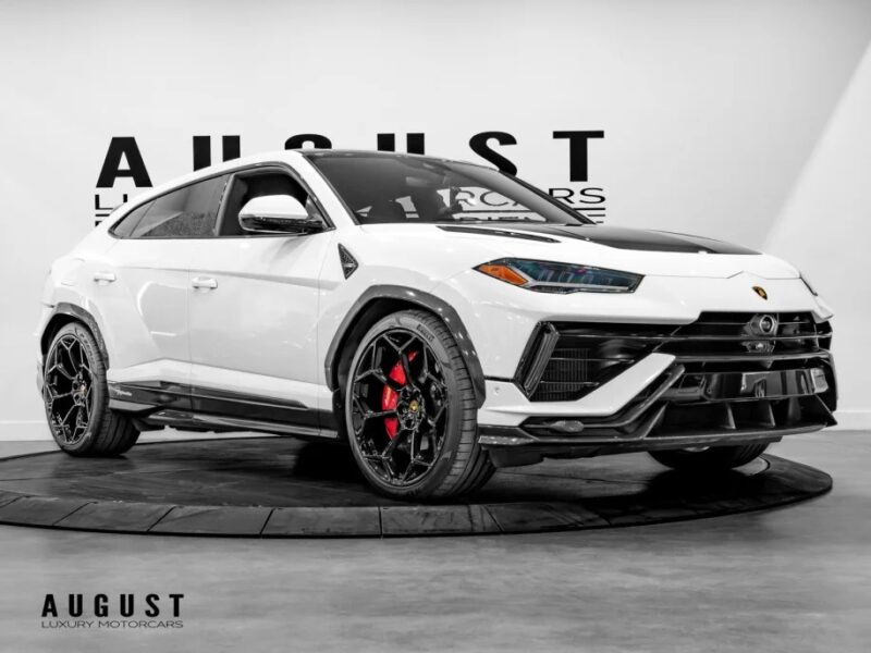 The Lamborghini Urus, a white luxury SUV with a sleek design, black accents, and red brake calipers, is elegantly displayed indoors on a turntable. As one of the best Lamborghinis available, it's an SUV for sale that combines style and performance seamlessly.