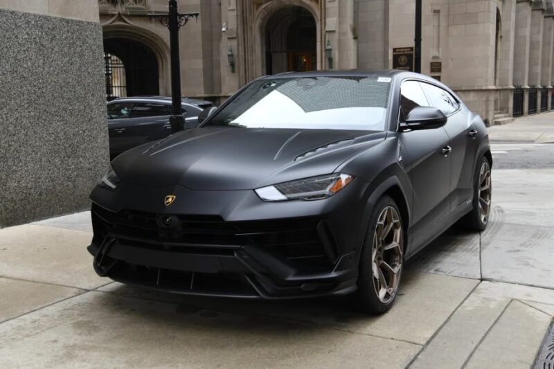 The sleek, matte black Lamborghini Urus SUV stands proudly on a city street, framed by elegant stone buildings in the background.