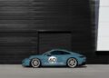 A blue Porsche 911 S/T with the number 60 on the side is elegantly parked in front of a sleek, black-paneled industrial building, reminiscent of those featured by RM Sotheby's.