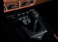 A close-up view of a Porsche 911 S/T's manual gear shift in a dark interior, with the iconic gear pattern and leather boot, reminiscent of RM Sotheby's exquisite collection.
