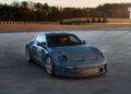 A sleek Porsche 911 S/T sports car sits elegantly on a paved surface, surrounded by lush trees against clear skies, awaiting its moment of excitement at the upcoming auction.
