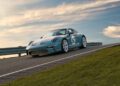 A sleek Porsche 911 S/T, adorned with the number 60, is parked on a sloped road. The car gleams under the clear sky, flanked by a guardrail and lush grass, reminiscent of an elegant listing at RM Sotheby's.