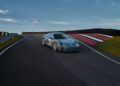 A sleek Porsche 911, emblazoned with the number 60, elegantly navigates the race track beneath a vast blue sky adorned with clouds.