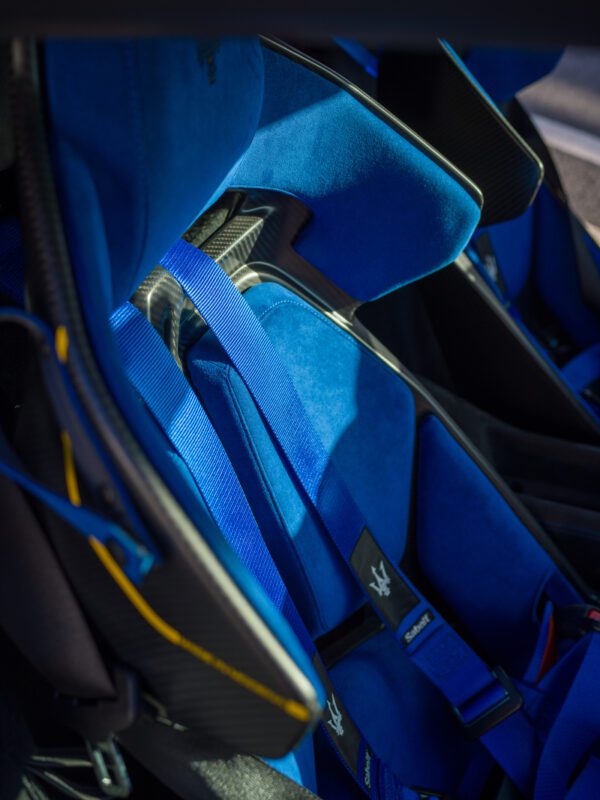 Close-up of blue racing-style car seats with harnesses in a vehicle interior.