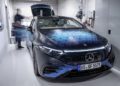 The "Solid State" branded electric car, enhanced by cutting-edge EV battery technology, is parked in a sleek modern garage. Nearby, a person blurs in motion, embodying the innovation reminiscent of F1 engineers and inspired by a touch of Mercedes-Benz craftsmanship.