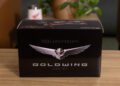 A special edition black box marked with "50th Anniversary Goldwing Since 1975" in silver text and a stylized wing emblem gracefully rests on a wooden surface, accompanied by a plant and blurred background.