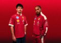 Two men in red Ferrari-branded clothing stand against a vivid red background, embodying the spirit of the PUMA x Scuderia Ferrari Replica Collection. Both look confidently at the camera, celebrating the 20th Anniversary of this iconic collaboration.