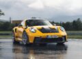 A yellow Porsche 992 911 GT3 RS sits elegantly on a wet road beneath a brooding, cloudy sky, its Michelin tires ready for any challenge.