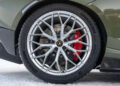 Close-up of a Lamborghini car wheel with intricate alloy rim design, red brake caliper, and Bridgestone tire, ready for a snow driving experience in Livigno.