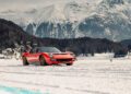 A red classic sports car, a Lamborghini Polo Storico masterpiece, navigates the snowy terrain with snow-covered mountains in the backdrop of St. Moritz.
