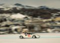 A sleek Lamborghini sports car races across a snowy landscape, with blurred mountains and buildings in the background, capturing the exhilarating spirit of I.C.E. St. Moritz.