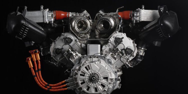 Close-up of a complex Lamborghini engine against a black background, featuring multiple components, orange cables, and metal parts symmetrically arranged within its 900HP powertrain.