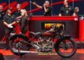 A vintage motorcycle takes center stage at a Mecum Auctions event in Las Vegas. Enthusiastic bidders in the background are fully engaged in the electrifying auction process.