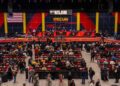 In a bustling indoor auction scene in Las Vegas, rows of eager attendees are seated as gleaming motorcycles take center stage. A large screen announces a bid of $825,000 at the Mecum Auctions event, while an American flag proudly hangs nearby.