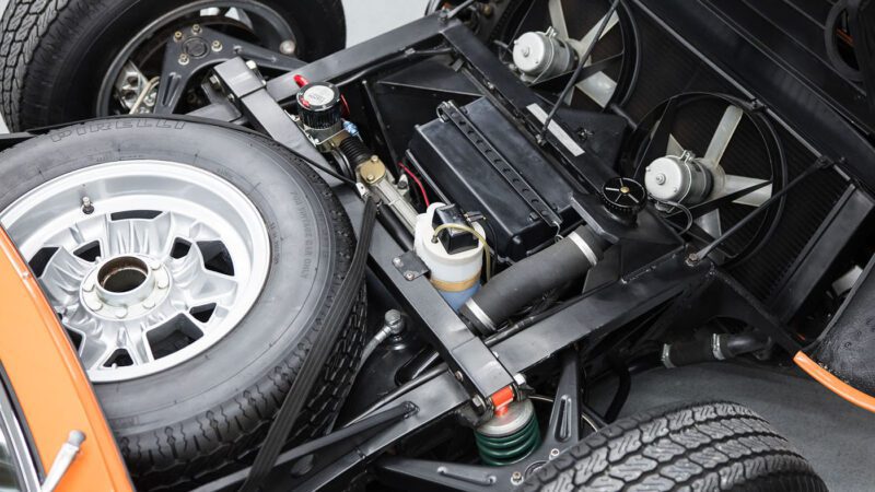 Close-up view of a Lamborghini Miura's engine compartment, revealing a spare tire, cooling fans, and other mechanical components in this vintage marvel. A true testament to automotive artistry that could be seen at events like Broad Arrow Auctions at Amelia Island.