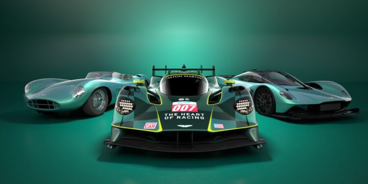 Three green Aston Martin cars, including a sleek Valkyrie Hypercar, are displayed in a row. The center car proudly features "007" and "The Heart of Racing" emblazoned on it.