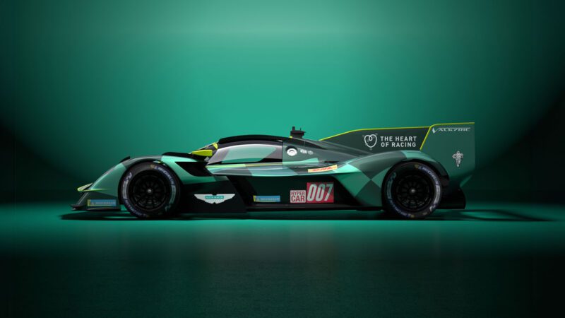 The sleek, green race car showcasing "The Heart of Racing" and "007" hints at its IMSA debut. Set against a lush green backdrop, it embodies the spirit of an Aston Martin Valkyrie on the track.