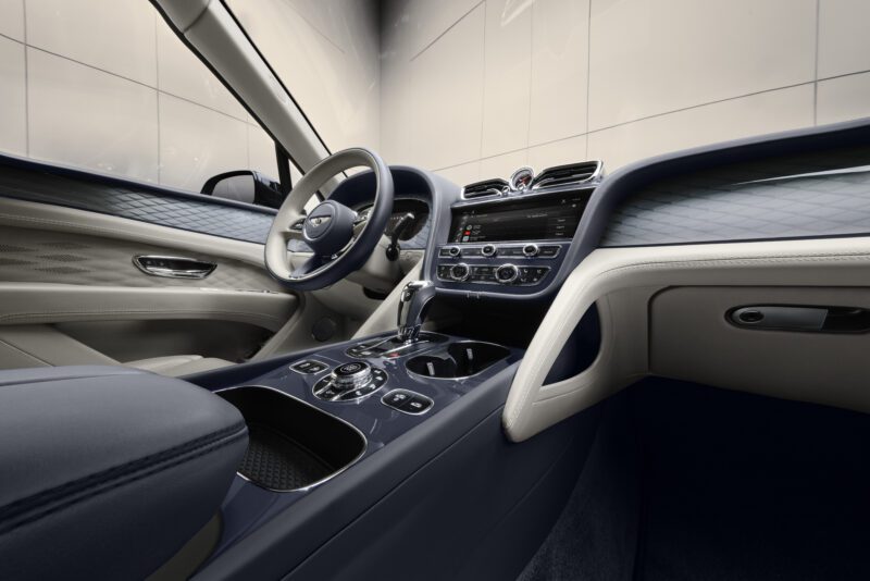 Interior mobil mewah yang menampilkan desain dasbor yang ramping, layar layar sentuh, kursi kulit, dan roda kemudi modern, dengan penekanan pada detail yang elegan dan hasil akhir kelas atas.