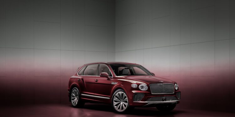 A maroon luxury SUV is parked in a minimalist, gradient-colored room with a reflective floor.