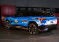 The blue Chevrolet Blazer EV, an official pace car for the Indy 500, is parked indoors near red tool cabinets, evoking the thrill of events like the Daytona 500.
