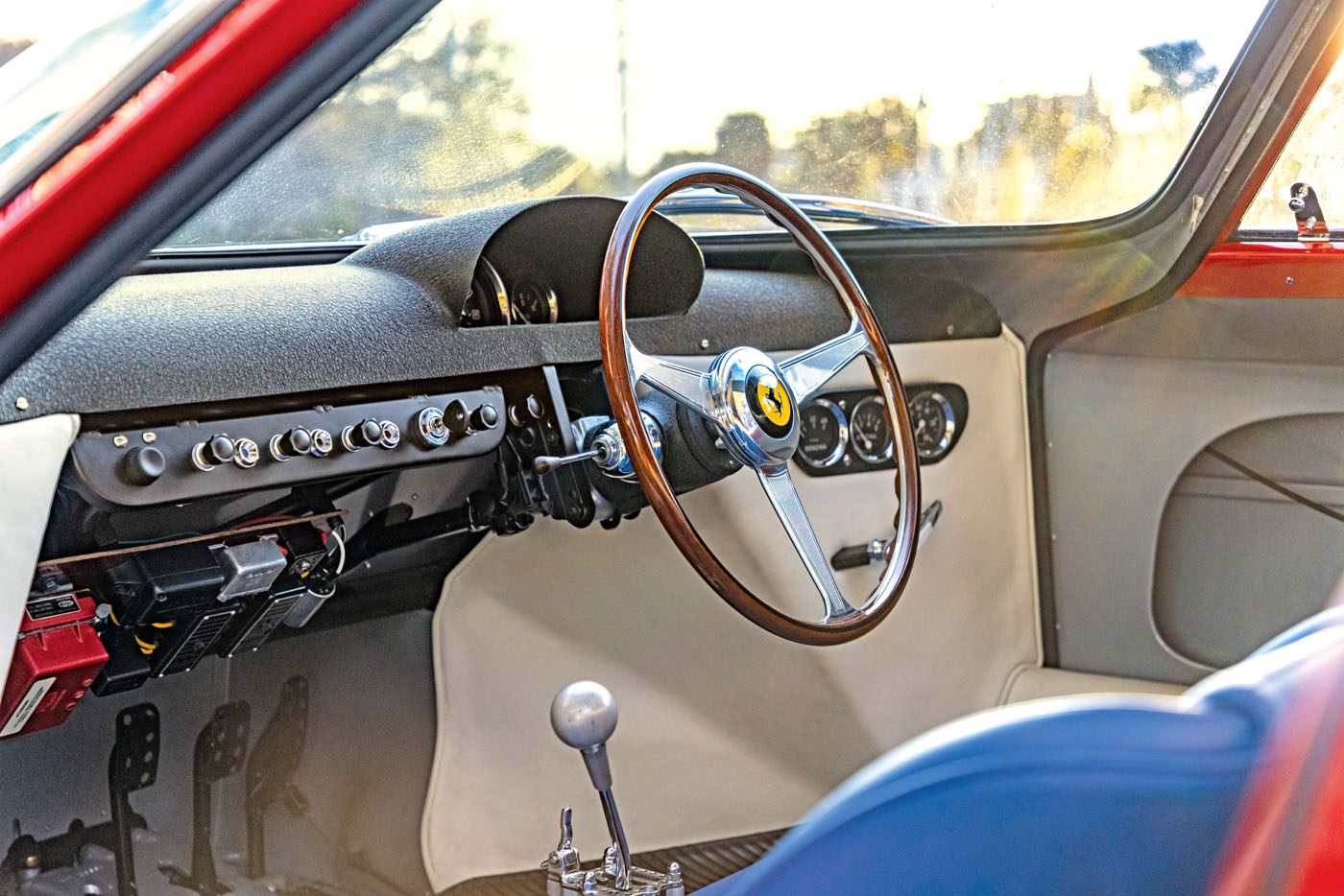 The interior of this classic car, reminiscent of the prestigious Cavallino Classic, boasts a wooden steering wheel, dashboard controls, and a manual gear shift—a nod to the timeless elegance celebrated in models like the Ferrari 250 LM.