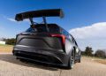 A sleek black Chevrolet race car with a large rear spoiler is parked on a paved road, set against a clear blue sky, embodying the spirit of NASCAR.