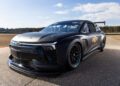 A sleek black Chevrolet race car, possibly from the NASCAR Prototype lineup, tears down the track under a partly cloudy sky, showcasing both its front and side view.