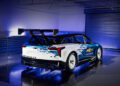 A Chevrolet race car featuring a prominent rear wing and a blue and white pixelated design, showcasing the iconic Chevrolet logo. This impressive NASCAR Prototype is parked indoors under striking blue lighting.