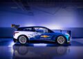A Chevrolet NASCAR Prototype, featuring striking blue, white, and black graphics and a prominent spoiler, is showcased indoors under bright lighting.