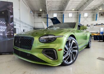 A green luxury Bentley Denver is parked indoors near a jet, showcased with sleek, modern styling and large alloy wheels, embodying the sophistication found in the duPont REGISTRY.