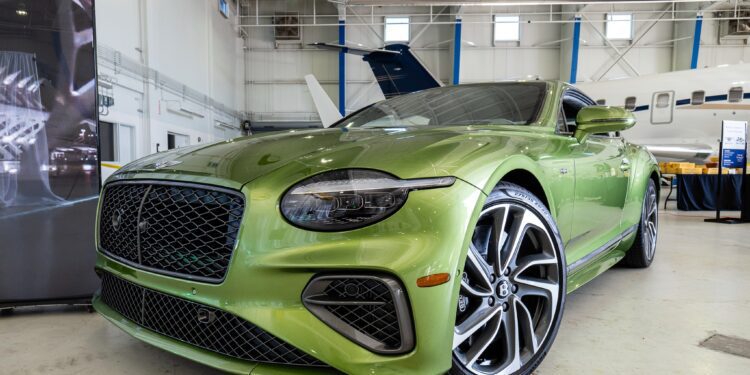 A green luxury Bentley Denver is parked indoors near a jet, showcased with sleek, modern styling and large alloy wheels, embodying the sophistication found in the duPont REGISTRY.