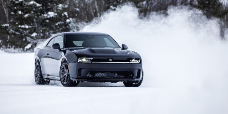 A black AWD muscle car slices through the swirling snow on a secluded road, with trees standing majestically in the background. This Dodge Charger proves its resilience as it tackles the wintry elements with ease.