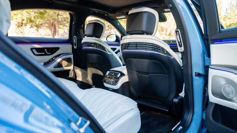 Interior view of a luxury car showing rear seats, a control panel, and ambient lighting on the doors.