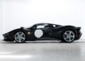 Side view of a sleek black Ferrari sports car with a white circular decal on the door, parked indoors in Beverly Hills, highlighting its aerodynamic design and silver alloy wheels.