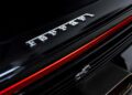 In the heart of Beverly Hills, a sleek black Ferrari Daytona SP3 stands out with its iconic logo on the rear, highlighted by a striking red light bar above the emblem.