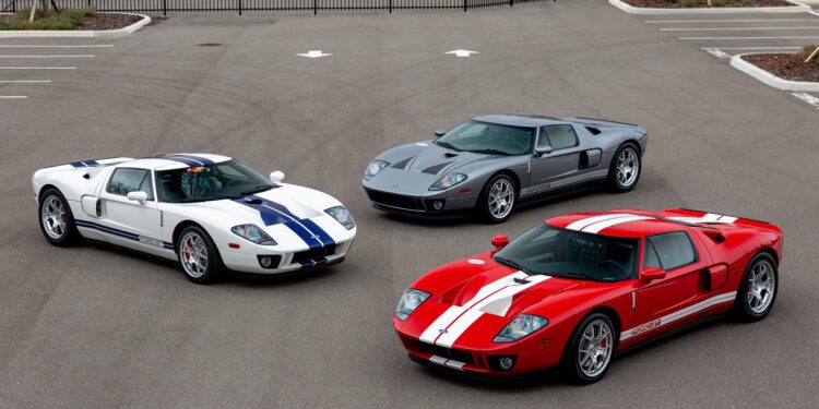 Three iconic Ford GT cars, including a rare 2006 model, are parked side by side: one white with blue stripes, one sleek grey, and a striking red with white stripes. These beauties make any car enthusiast eager to win the bid for such vintage treasures.