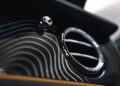 Close-up of a Bentley car dashboard, featuring a circular air vent with sleek, curved wood paneling and a control knob, showcasing the elegance of Mulliner's bespoke craftsmanship.