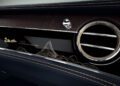 Close-up of a car dashboard featuring a chrome air vent, black and brown panel, and gold detailing. The text "1 of 8 by Bentley Mulliner" highlights its exclusivity within the Mulliner Bespoke Collections.