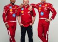 Three men in red racing attire stand together; two in full racing suits and sneakers flank a man in a red shirt and black pants, reminiscent of the bold style of Ferrari's legendary F1 car.