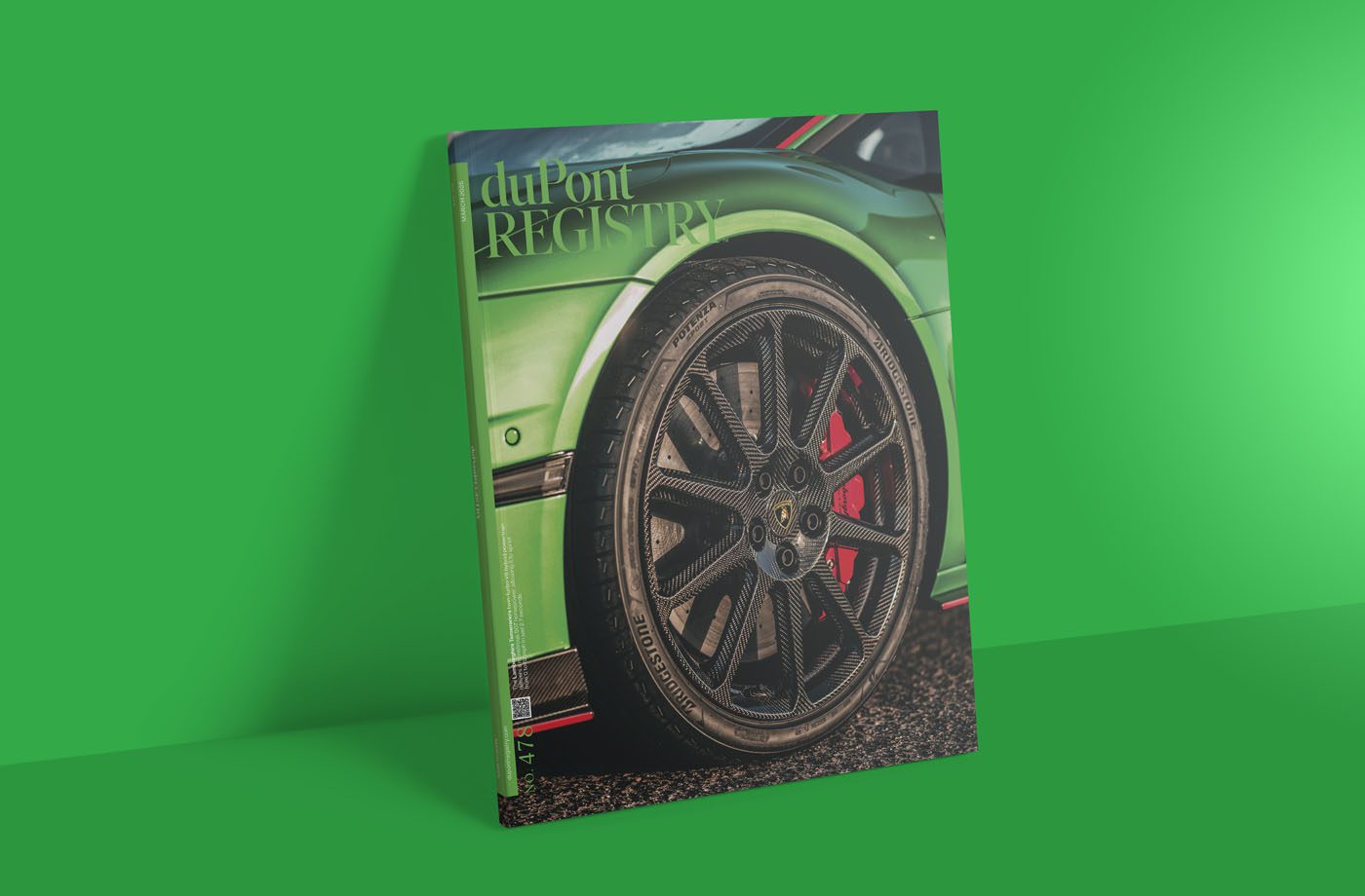 A magazine cover lies on a green surface, showcasing a close-up of a car's front wheel and part of the body. The top is emblazoned with "duPont REGISTRY," hinting at its March 2025 edition.