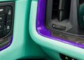A close-up of a Porsche car interior showcases turquoise and purple trim with carbon fiber accents. The dashboard reveals the signature push start/stop button, while TECHART-inspired enhancements amplify the luxury feel surrounding the door lock buttons.