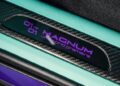 Close-up of a car plaque displaying "01 of 01 MAGNUM, U.S. world premiere," featuring a sophisticated carbon fiber texture with teal and purple accents, reminiscent of the sleek design elements found in a TECHART Porsche Cayenne.
