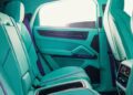Interior of a car featuring turquoise seats with purple accents and a door panel. Sunlight streams through the window, giving the space an almost magical glow—a perfect blend of style reminiscent of a sleek Porsche Cayenne.