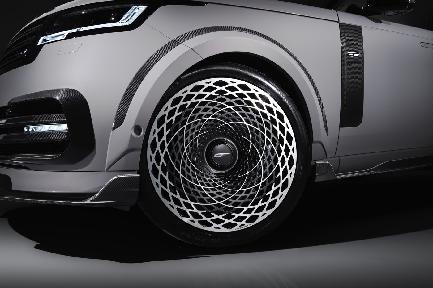 Close-up of a gray car's front wheel from the Velocity Edition, featuring an intricate, spiraling black-and-white pattern on the rim against a dark background—a true aesthetic marvel.