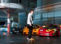 A skateboarder glides effortlessly indoors near parked sports cars in a modern showroom at McLaren Headquarters, with its glass walls and sleek metallic structures showcasing the stunning Artura Spider.