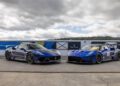 Two blue Maserati sports cars, including the sleek GT2 Stradale, are parked side by side on a Spanish racetrack with overcast skies in the background.